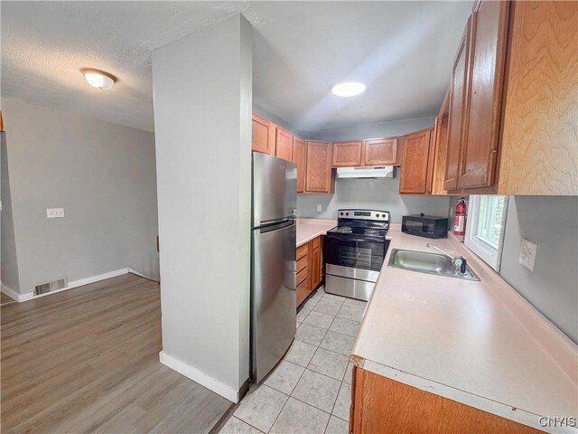 63 Groton Ave, Cortland, NY 13045 - kitchen featuring appliances with stainless steel finishes, light countertops, under cabinet range hood, brown cabinets, and light wood-style floors