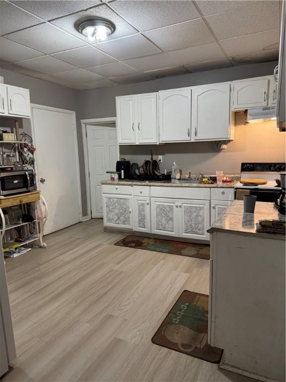 280 Ave D, Rochester, NY 14621 - kitchen with range with electric cooktop, range hood, stainless steel microwave, a drop ceiling, and white cabinetry