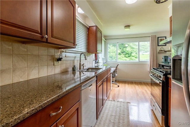 368 Northfield Way, Camillus, NY 13031 - kitchen with stainless steel appliances, light wood-style flooring, decorative backsplash, dark stone counters, and exhaust hood