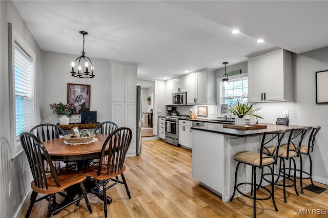 17 E Ave, Leroy, NY 14482 - kitchen featuring stainless steel appliances, a peninsula, dark countertops, a kitchen breakfast bar, and a chandelier
