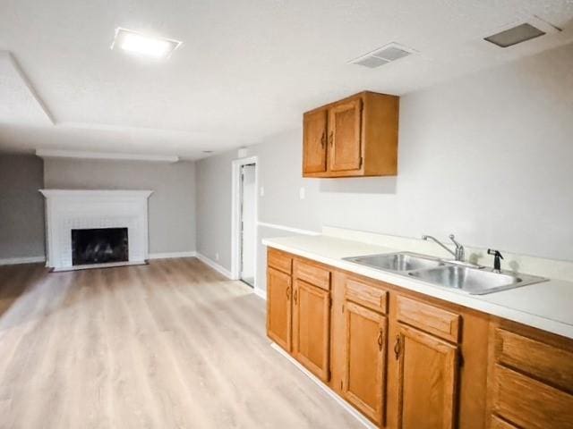22 Yorkshire Rd, Irondequoit, NY 14609 - kitchen with light countertops, light wood-type flooring, brown cabinetry, and a brick fireplace
