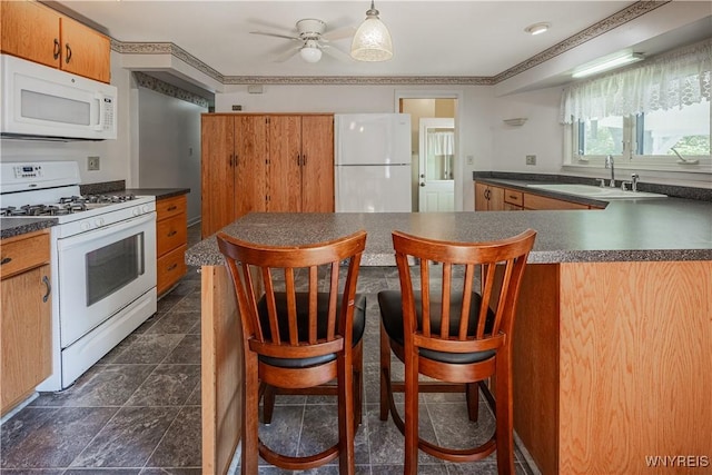 18 Eisenhower Dr, Lockport-City, NY 14094 - kitchen featuring white appliances, dark countertops, ceiling fan, a kitchen breakfast bar, and a peninsula