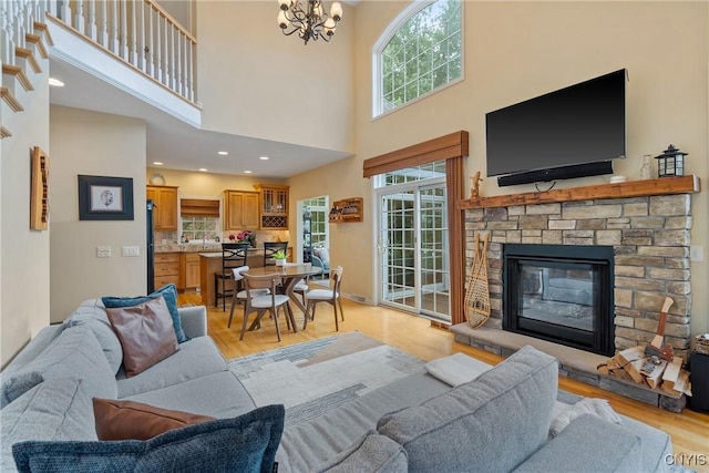 84 Krystyna Ln Unit 6, Cato, NY 13080 - living area featuring light wood-style flooring, a fireplace, a towering ceiling, and a chandelier
