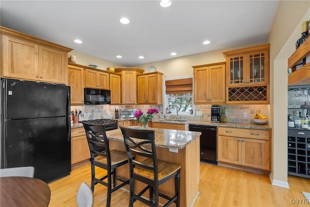84 Krystyna Ln Unit 6, Cato, NY 13080 - kitchen with black appliances, light stone countertops, light wood finished floors, a breakfast bar, and glass insert cabinets