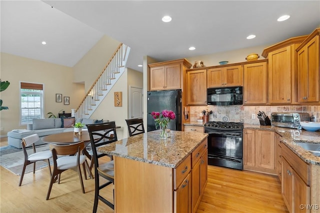 84 Krystyna Ln Unit 6, Cato, NY 13080 - kitchen with black appliances, light wood-style floors, a kitchen island, light stone countertops, and backsplash