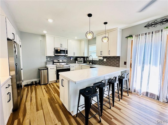 300 Hillsdale Ave, Syracuse, NY 13206 - kitchen featuring stainless steel appliances, a peninsula, light wood-style floors, backsplash, and a breakfast bar area