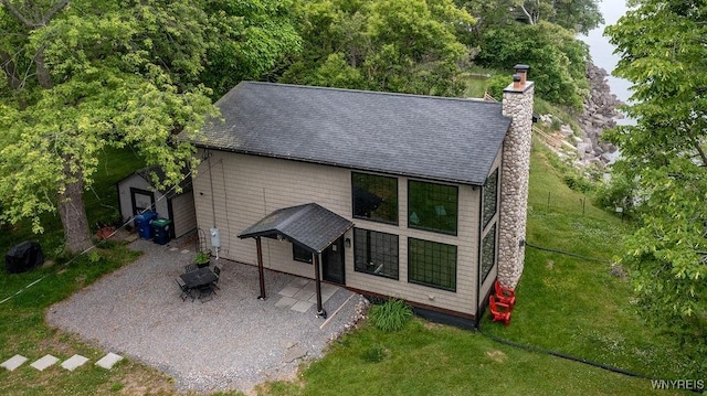 2300 Washington Ave, Wilson, NY 14172 - back of property featuring a patio, a chimney, a yard, a shingled roof, and a shed
