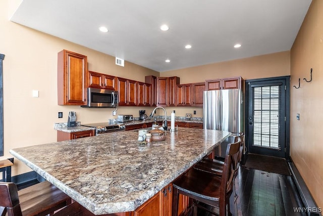 2300 Washington Ave, Wilson, NY 14172 - kitchen featuring appliances with stainless steel finishes, a kitchen bar, recessed lighting, dark stone countertops, and a center island with sink