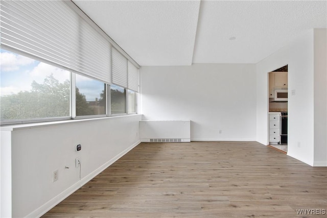 1088 Delaware Ave Unit 3B, Buffalo, NY 14209 - unfurnished room featuring wood finished floors, a textured ceiling, and radiator heating unit