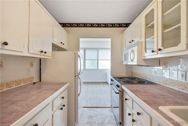 1088 Delaware Ave Unit 3B, Buffalo, NY 14209 - kitchen with white appliances, tile countertops, glass insert cabinets, tasteful backsplash, and a textured ceiling