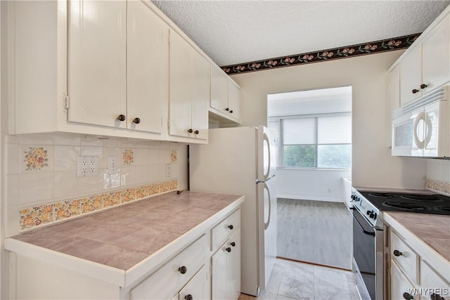 1088 Delaware Ave Unit 3B, Buffalo, NY 14209 - kitchen with white appliances, white cabinetry, tasteful backsplash, tile countertops, and a textured ceiling
