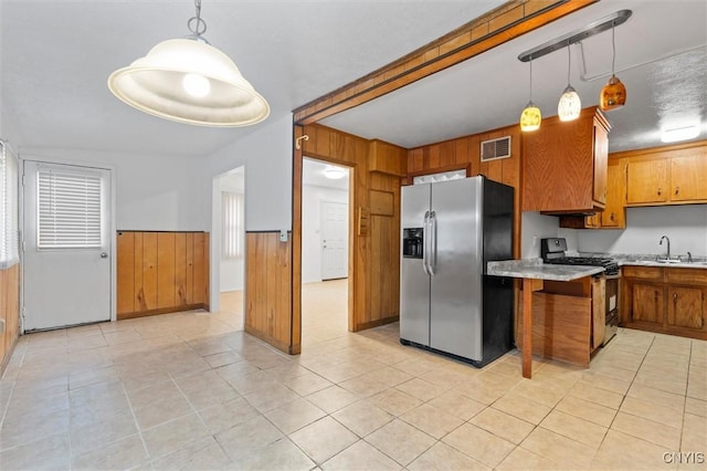 200 Vardon St, Salina, NY 13088 - kitchen featuring stainless steel fridge, black gas stove, brown cabinets, light countertops, and wooden walls