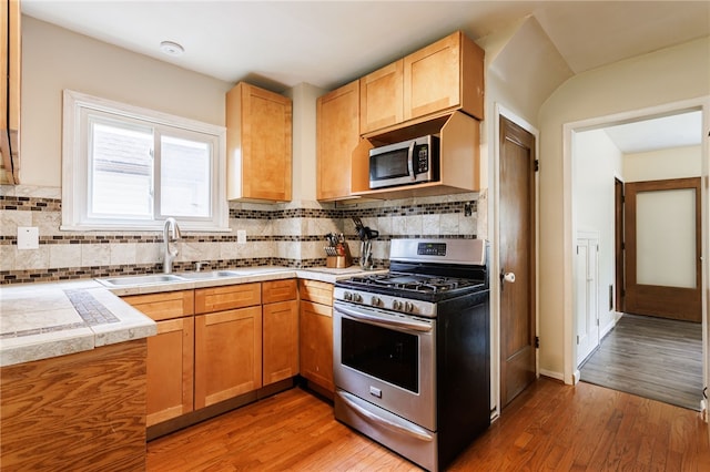 2092 Titus Ave, Irondequoit, NY 14622 - kitchen featuring appliances with stainless steel finishes, light wood-style flooring, decorative backsplash, light countertops, and light brown cabinetry