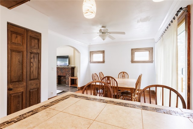 2092 Titus Ave, Irondequoit, NY 14622 - dining room with a fireplace, a ceiling fan, arched walkways, crown molding, and wood finished floors