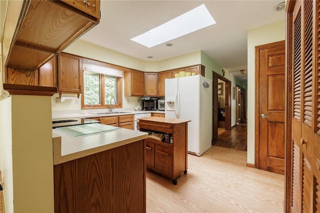 745 Maple Dr, Webster, NY 14580 - kitchen with white appliances, a skylight, light wood-style floors, a center island, and brown cabinets