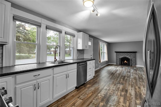 25 Cresthaven Dr, Cheektowaga, NY 14225 - kitchen featuring stainless steel appliances, a brick fireplace, dark countertops, white cabinets, and dark wood finished floors