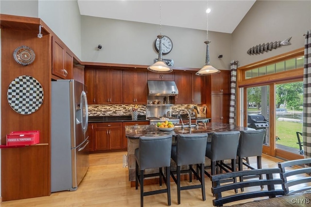 32 Coblesub Rd, West Monroe, NY 13036 - kitchen with stainless steel refrigerator with ice dispenser, high vaulted ceiling, under cabinet range hood, decorative backsplash, and a kitchen breakfast bar