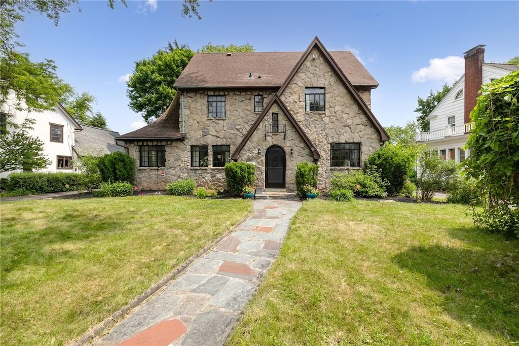 22 Rhinecliff Dr, Brighton, NY 14618 - tudor home featuring stone siding, a front yard, and roof with shingles