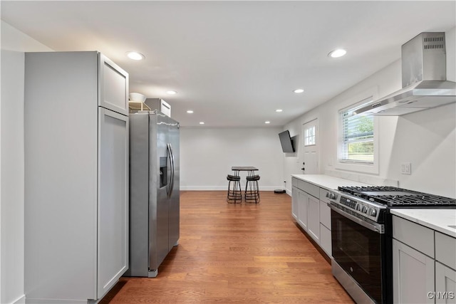 7446 Collamer Rd, Manlius, NY 13057 - kitchen featuring appliances with stainless steel finishes, wall chimney range hood, light wood finished floors, recessed lighting, and light countertops