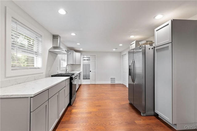 7446 Collamer Rd, Manlius, NY 13057 - kitchen featuring wall chimney exhaust hood, appliances with stainless steel finishes, recessed lighting, wood finished floors, and gray cabinets
