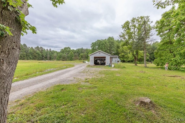 7446 Collamer Rd, Manlius, NY 13057 - view of grassy yard with an outbuilding, gravel driveway, a detached garage, and a forest view