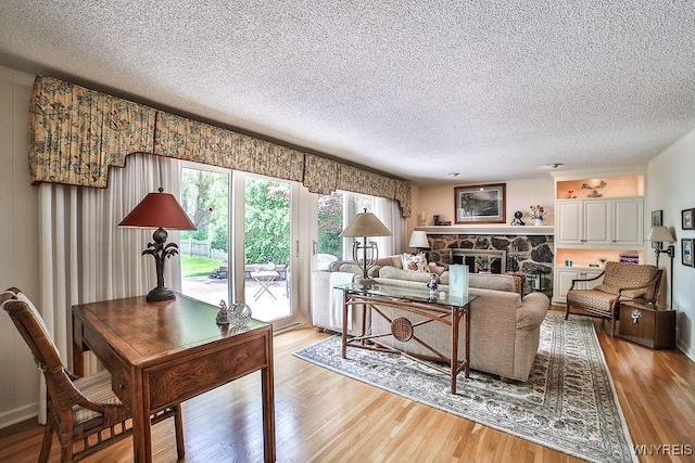 177 Foxpoint W, Amherst, NY 14221 - living room with light wood finished floors, a textured ceiling, and a stone fireplace