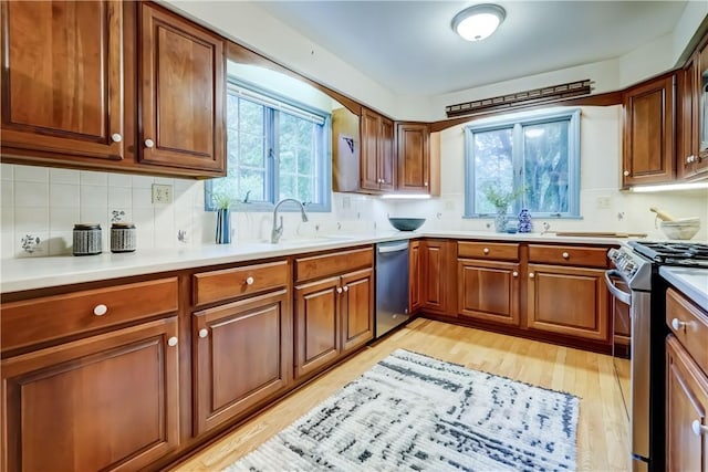 107 Fieldston Ter, Brighton, NY 14610 - kitchen featuring appliances with stainless steel finishes, light wood-type flooring, tasteful backsplash, brown cabinets, and light countertops