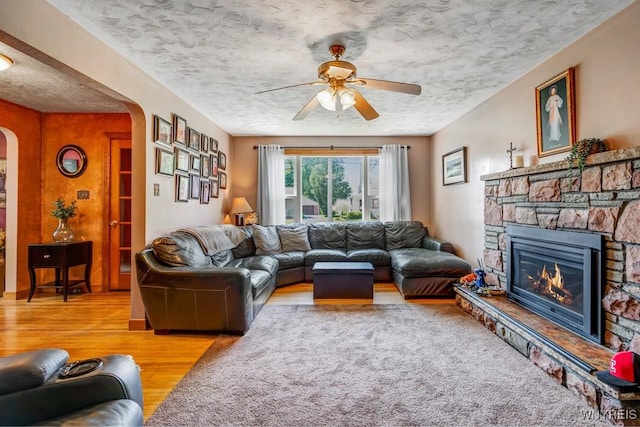 8652 Griffon Ave, Niagara Falls, NY 14304 - living room with arched walkways, a ceiling fan, wood finished floors, a fireplace, and a textured ceiling