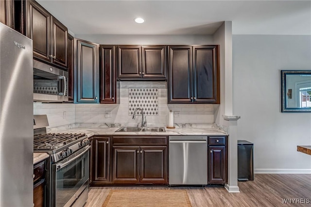 4217 Arthur Ct, Hamburg, NY 14075 - kitchen featuring appliances with stainless steel finishes, tasteful backsplash, dark brown cabinets, light wood-style floors, and light stone countertops