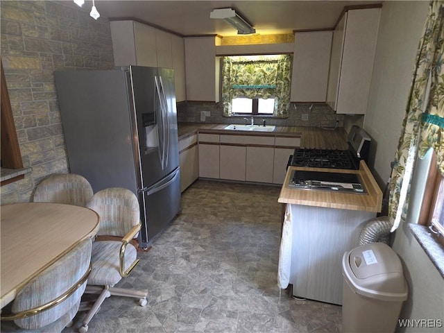 2595 Jerauld Ave, Niagara Falls, NY 14305 - kitchen with stainless steel refrigerator with ice dispenser, backsplash, stone finish flooring, range with gas stovetop, and white cabinetry