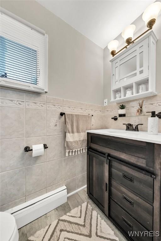 48 Meaford Rd, Cheektowaga, NY 14215 - half bathroom with a baseboard radiator, tile walls, vanity, wood finished floors, and wainscoting