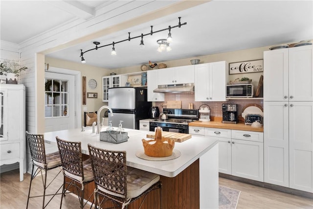 639 Plank Rd, Penfield, NY 14580 - kitchen featuring black appliances, under cabinet range hood, light wood-style flooring, white cabinets, and decorative backsplash