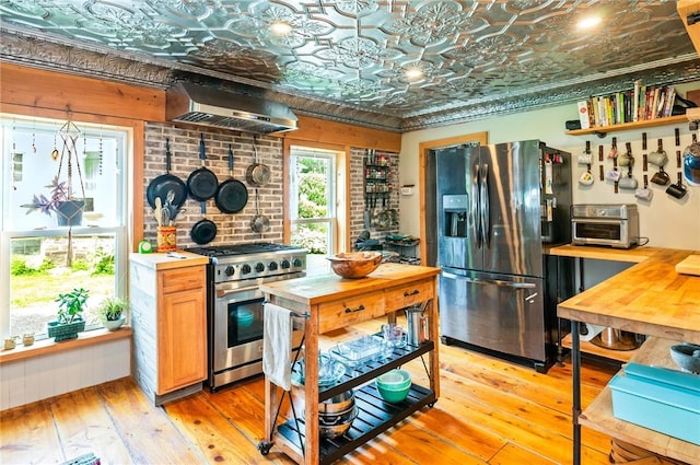 258 E State St, Albion, NY 14411 - kitchen with appliances with stainless steel finishes, under cabinet range hood, an ornate ceiling, wood counters, and light wood finished floors