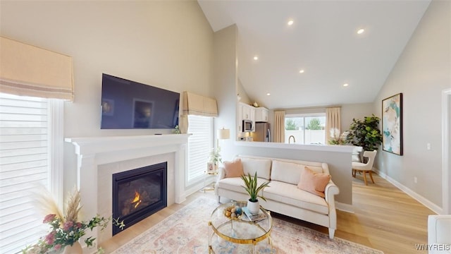 37A Stonham Pl, Amherst, NY 14221 - living area featuring a glass covered fireplace, high vaulted ceiling, light wood-style floors, and recessed lighting