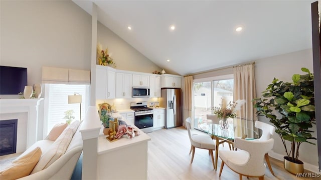 37A Stonham Pl, Amherst, NY 14221 - living room with high vaulted ceiling, light wood-style floors, a glass covered fireplace, and recessed lighting