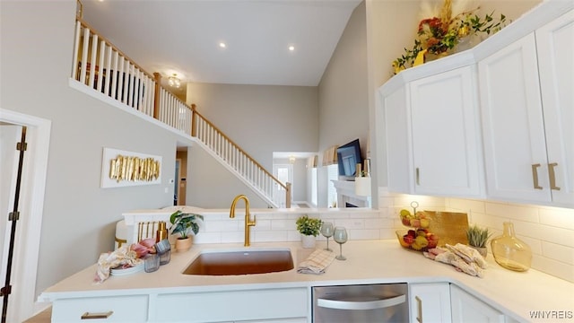 37A Stonham Pl, Amherst, NY 14221 - kitchen featuring stainless steel dishwasher, light countertops, white cabinetry, backsplash, and a towering ceiling