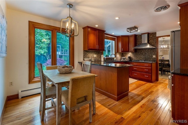 20 Dan Troy Dr, Amherst, NY 14221 - kitchen featuring wall chimney exhaust hood, a peninsula, a chandelier, light wood finished floors, and recessed lighting