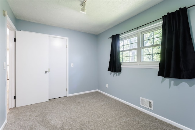 32 Princess Dr, Henrietta, NY 14623 - unfurnished bedroom featuring carpet, a textured ceiling, track lighting, and a closet