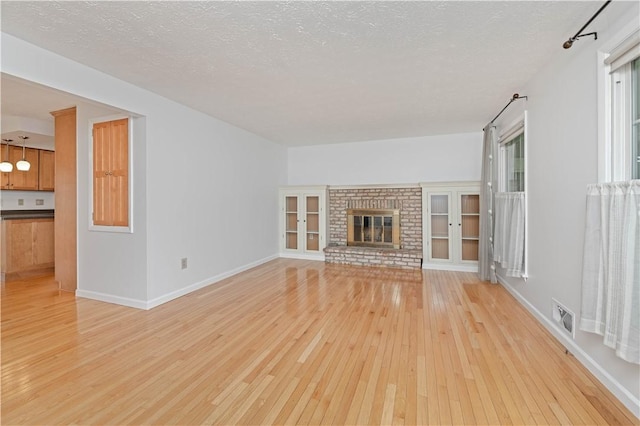 39 Southwind Ct, Greece, NY 14626 - unfurnished living room featuring light wood finished floors, a textured ceiling, and a brick fireplace