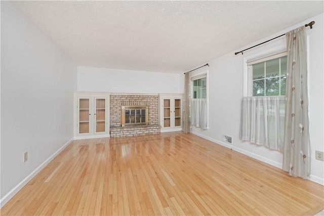 39 Southwind Ct, Greece, NY 14626 - unfurnished living room featuring light wood finished floors, a textured ceiling, and a brick fireplace