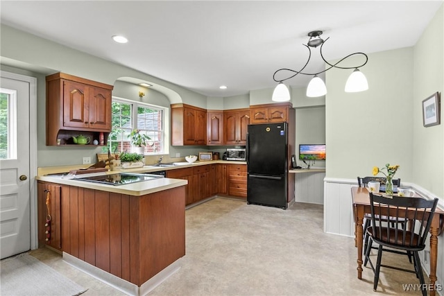 63 Chauncey Ln, Orchard Park, NY 14127 - kitchen featuring black appliances, a peninsula, light countertops, brown cabinetry, and a wainscoted wall