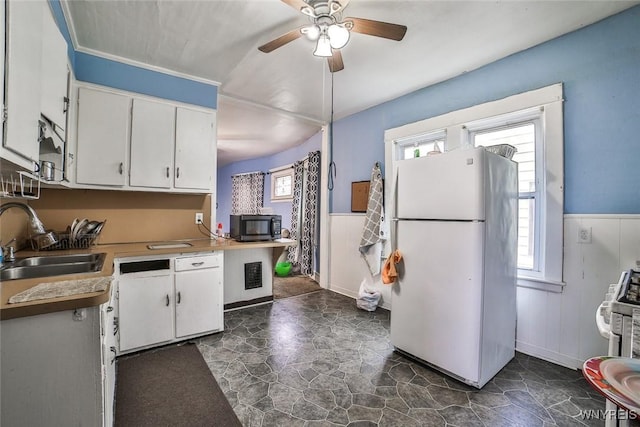 132 Ryan St, Buffalo, NY 14210 - kitchen with freestanding refrigerator, black microwave, a wainscoted wall, white cabinets, and a ceiling fan
