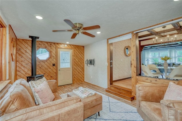 1541 Shoecraft Rd, Penfield, NY 14526 - living area with wood finished floors, a wood stove, wood walls, ceiling fan, and a textured ceiling