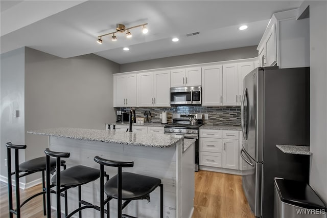 184 14th St, Buffalo, NY 14213 - kitchen with appliances with stainless steel finishes, white cabinets, light stone countertops, a kitchen bar, and decorative backsplash