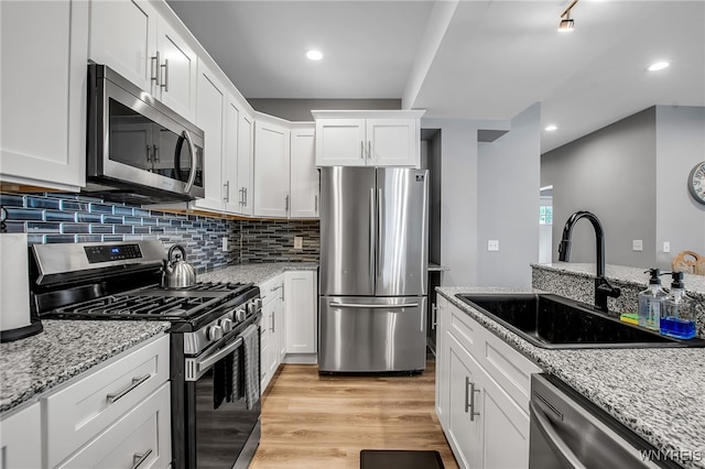 184 14th St, Buffalo, NY 14213 - kitchen featuring appliances with stainless steel finishes, white cabinets, backsplash, light wood-style flooring, and light stone countertops