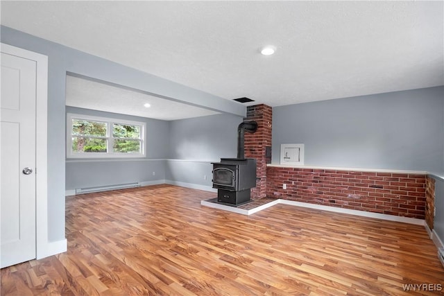 2540 Snyder Rd, Orangeville, NY 14167 - unfurnished living room with a baseboard radiator, wood finished floors, a wood stove, and a textured ceiling