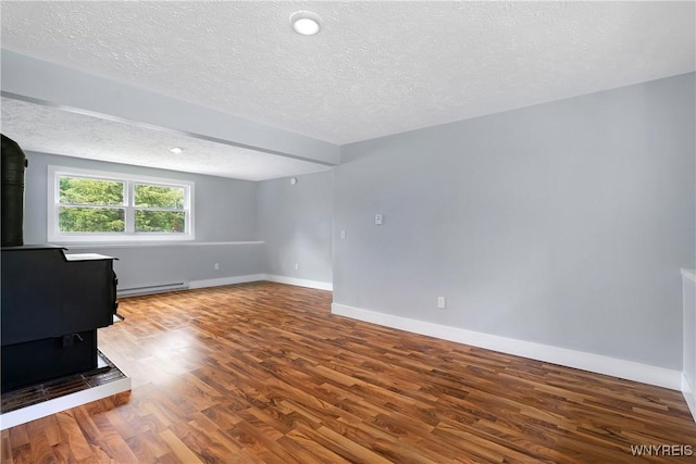 2540 Snyder Rd, Orangeville, NY 14167 - unfurnished room with baseboard heating, a wood stove, wood finished floors, and a textured ceiling