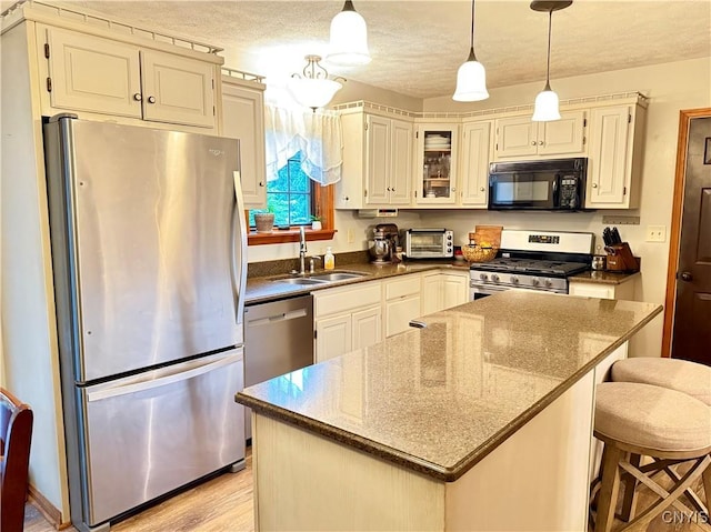 550 Sayles St, Oneida-Inside, NY 13421 - kitchen featuring appliances with stainless steel finishes, a kitchen island, pendant lighting, glass insert cabinets, and a textured ceiling