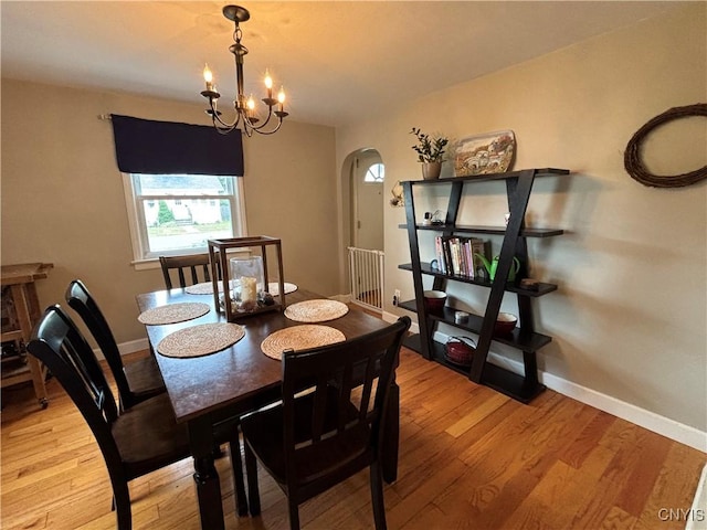 301 Loma Ave, Syracuse, NY 13208 - dining space featuring arched walkways, light wood-style flooring, and a chandelier