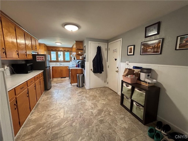 301 Loma Ave, Syracuse, NY 13208 - kitchen featuring black microwave, brown cabinetry, light countertops, range, and light stone finish floors